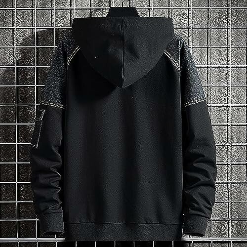 Back view of a black hoodie with grid wall background