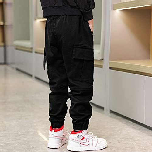 Child wearing black jogger pants and white sneakers.