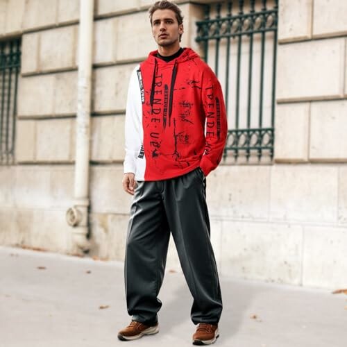 Man wearing red hoodie and gray pants standing on sidewalk