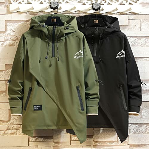 Two hooded jackets, olive green and black, hung on hangers against a brick wall.